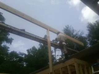 Carpenter setting a ridge beam over a new addition frame — Ice Dam Removal by Roofing Brothers in Holladay