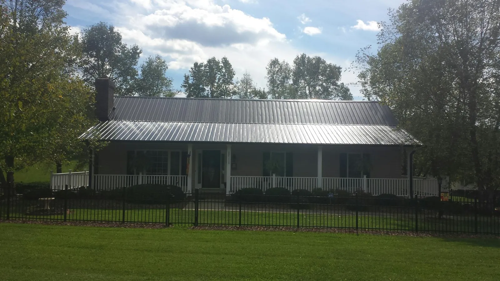Gray metal roof on a brick ranch with a full width front porch — Gutter Guard Installation work by our crew in Holladay