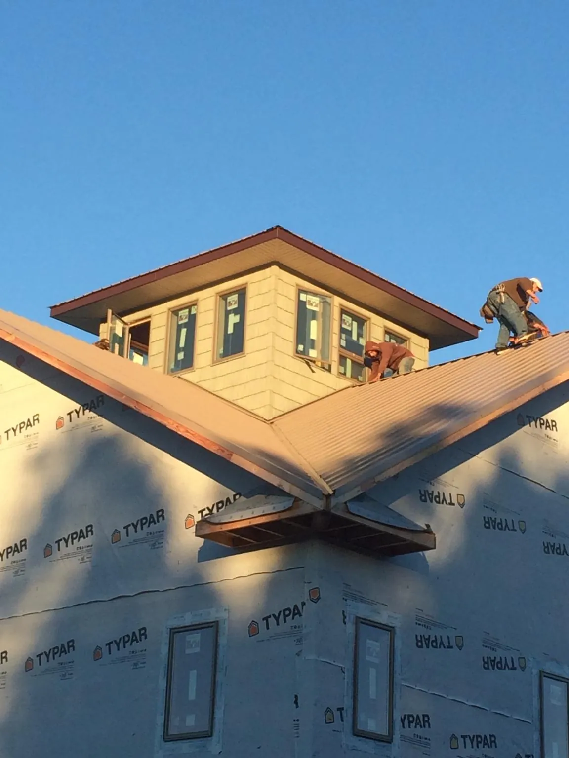 Roofers working around a rooftop cupola on a new metal roof at sunset — Roof Waterproofing in Holladay by Roofing Brothers
